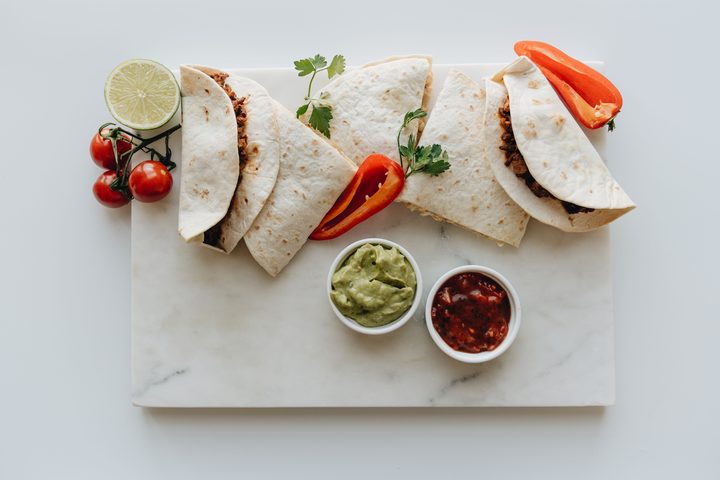 Tacos with guacamole and salsa on a marble board